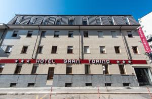 都灵Hotel Gran Torino的上面有红色标志的酒店大楼