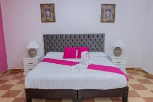 切图马尔OYO Hotel Marías,Aeropuerto Internacional de Chetumal的卧室配有一张带粉红色枕头的大床