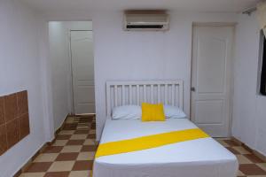 切图马尔OYO Hotel Marías,Aeropuerto Internacional de Chetumal的小卧室配有一张带黄色枕头的床