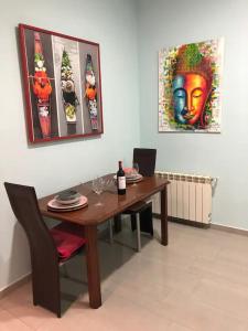 马德里APARTAMENTO PRIVADO CERCA DE IFEMA y AEROPUERTO的餐桌,配有一瓶葡萄酒和绘画