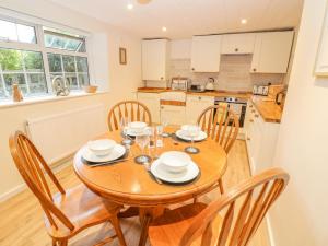 莱奇莱德Halfpenny Cottage的厨房以及带木桌和椅子的用餐室。