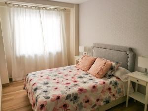 拉科鲁尼亚HyP - Esquina Primavera的一间卧室配有一张带花卉棉被的床和窗户。