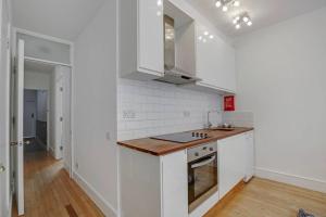 伦敦Flat C, Old Street的厨房铺有木地板,配有白色橱柜。