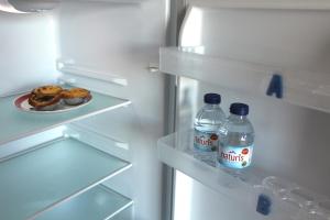 拉戈斯Guesthouse Felicidade的冰箱,装有两瓶水和一盘甜甜圈