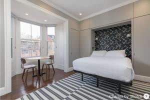 波士顿94 Charles Street by Thatch的一间卧室配有一张床、一张桌子和一个窗户。