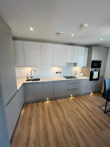 贝尔法斯特City Centre Luxury Apartments的厨房铺有木地板,配有白色橱柜。