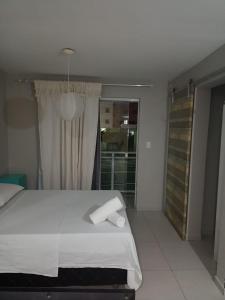 福塔莱萨Hotel Oiticica的卧室配有白色的床和窗户。