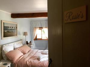 林肯Lut's Place的一间卧室配有一张带粉色床单的床和一扇窗户。