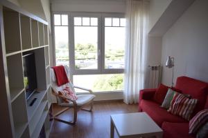 擞莫Apartamentos Somo1的客厅设有红色的沙发和窗户。