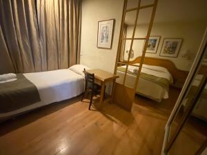 圣地亚哥Intimo Hotel Miraflores的一间卧室配有两张床、一张桌子和一面镜子