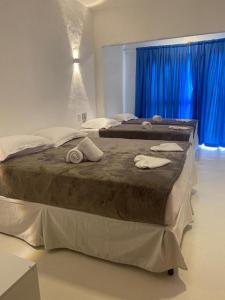 卡莫辛Pousada La Grécia的卧室内的两张床,配有蓝色窗帘