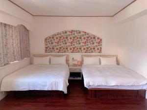台东旅行家商务会馆的配有白色床单和窗户的客房内的两张床