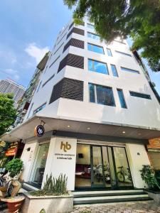 河内HB Serviced Apartment - 12 Trần Quý Kiên的一间高大的白色建筑,前面是商店