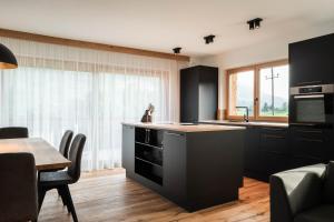 DorfHohe Tauern Lofts Panoramabahn by Alpina-Holiday的厨房配有黑色橱柜、桌子和用餐室。