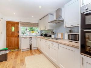 麦克尔斯菲尔德Fox Bank Cottage的白色的厨房配有白色橱柜和木地板