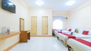 UrdanetaRedDoorz @ Goldland Spring Resort Urdaneta City的一间酒店客房,设有四张床和电视