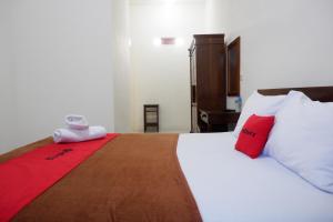 MontongbuwohReddoorz at Bale Eja Syariah Senggigi的一间卧室配有一张带红色和白色枕头的大床