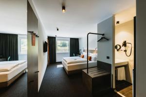 费尔德基希NIGHT INN Hotel Bahnhofcity Feldkirch的酒店客房带两张床和一间浴室