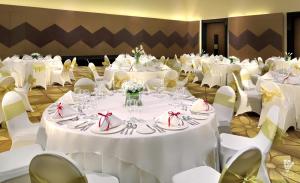 当格浪d'primahotel Tangerang的宴会厅配有白色的桌子和白色的椅子