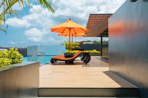 卡塔海滩Wekata Luxury的天井配有桌子、雨伞和长凳