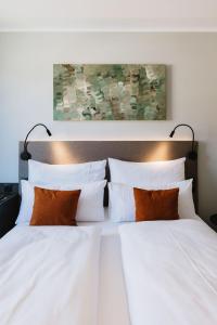 费尔德基希NIGHT INN Hotel Bahnhofcity Feldkirch的一张带白色床单和橙色枕头的床
