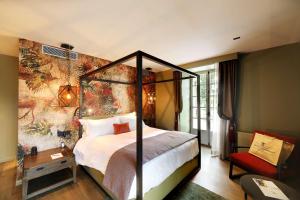 波特莱斯内吉米内城堡酒店的一间卧室配有一张天蓬床和一把椅子