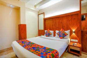 孟买FabExpress Super 7 Inn的一间卧室配有一张大床和木制床头板