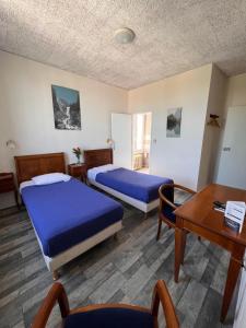 圣迪济耶尚巴尼酒店的客房设有两张床、一张桌子和一张桌子。