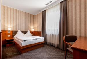 弗罗茨瓦夫巴斯洛弗罗茨瓦夫高级酒店的配有一张床、一张书桌和一扇窗户的酒店客房