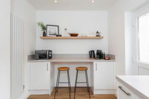 纽波特Crescent Apartments的厨房配有2张凳子和带微波炉的台面。