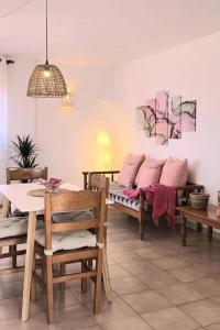 卡拉菲格拉Apartamentos Can Salas的用餐室配有桌子和带粉红色枕头的长椅