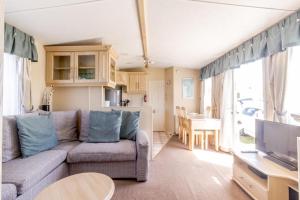 大雅茅斯By The Seaside Dog Friendly Caravan At Haven Hopton In Norfolk Ref 80015w的带沙发和桌子的客厅以及厨房。