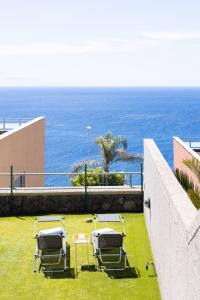 圣克鲁斯-德特内里费Chalet con vistas al mar en Santa Cruz de Tenerife的一群椅子坐在靠近海洋的草地上
