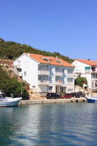 萨利Apartments and rooms by the sea Zaglav, Dugi otok - 8144的一座大型白色建筑,旁边停有汽车