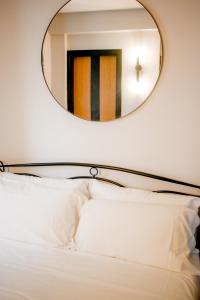 蒙泰伊索拉Sensole locanda contemporanea的床上方的镜子,配有白色枕头