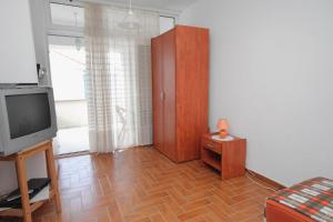 奈维斯Studio Njivice 5458a的客厅配有电视,铺有木地板