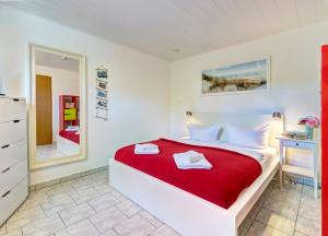 特拉森海德Bungalow Konrad的白色卧室配有红色的床和镜子