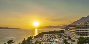 马卡尔斯卡Aminess Khalani Hotel的日落时分享有度假村和大海的景致