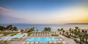 马卡尔斯卡Aminess Khalani Hotel的享有带游泳池和海洋的度假村的空中景致
