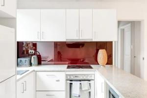 悉尼Bright 1 Bedroom Apartment in Lane Cove的厨房配有白色橱柜和炉灶烤箱。