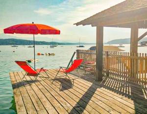 沃尔特湖畔佩莎赫Villa Gabriela的码头上两把椅子和一把雨伞