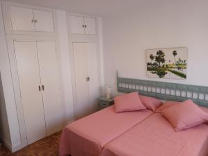马拉加NEW MARITIMO的卧室配有粉红色的床和白色橱柜