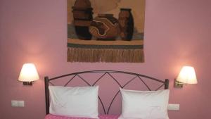 新马尔马拉斯House Roula的一张带两个白色枕头的床和墙上的绘画