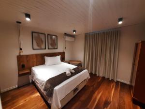 本图贡萨尔维斯Pousada Somenzi的卧室配有一张白色的大床,铺有木地板