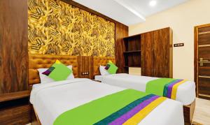 古瓦哈提Treebo Trend Spring Brook的酒店客房设有两张床,墙上挂有绘画作品