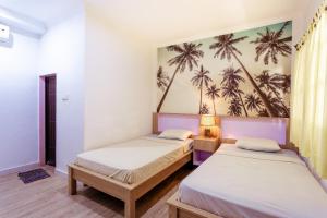 库塔Segara Sadhu Inn Kuta by ecommerceloka的墙上棕榈树间内的两张床