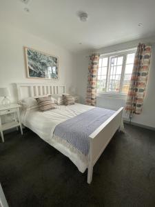 谢林汉姆The Crows Nest - Sheringham的卧室配有带枕头的大型白色床