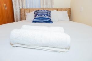 尼耶利The Stay Comfort的一张带白色床单和蓝色及白色枕头的床