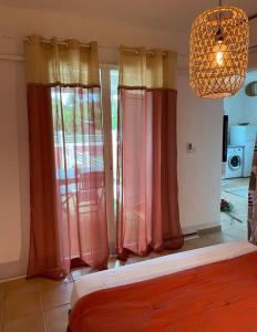 圣弗朗索瓦Appartement cosy & calme en Rez de villa的一间卧室配有红色和黄色的窗帘和吊灯。