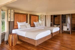 塞伦盖蒂Aurari Camp的卧室设有两张床,铺有木地板,设有窗户。